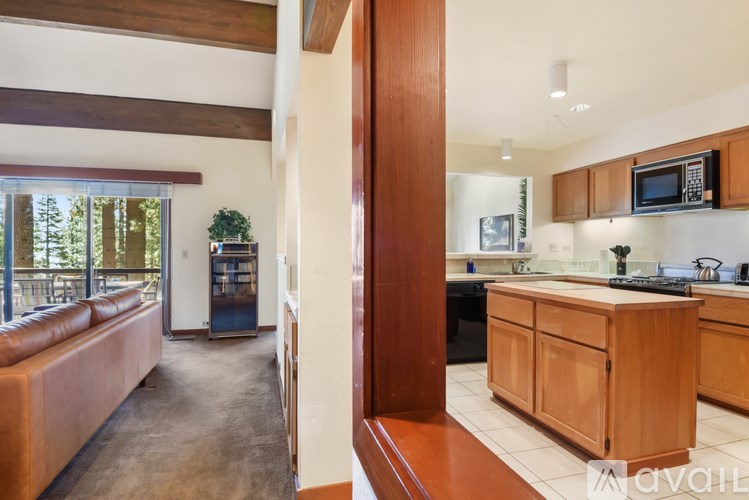 A modern kitchen with wooden cabinets and a brown leather couch.