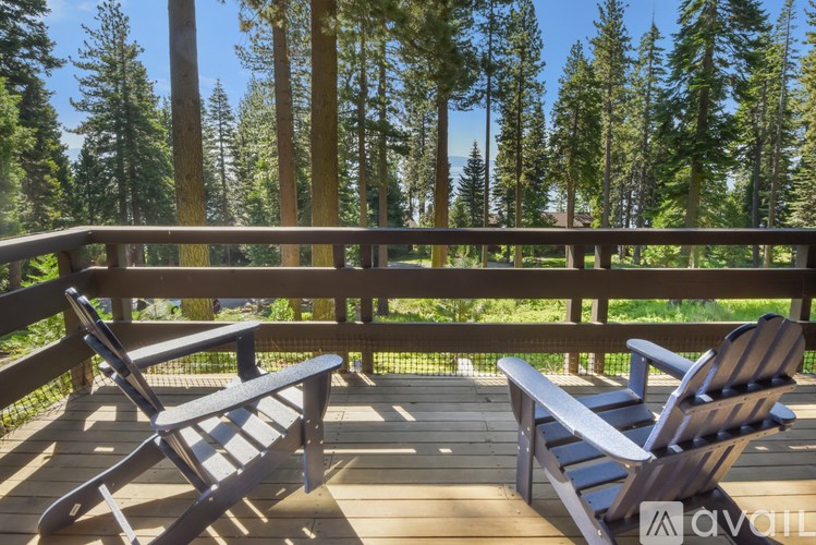 Two chairs on a wooden deck overlooking a forest.