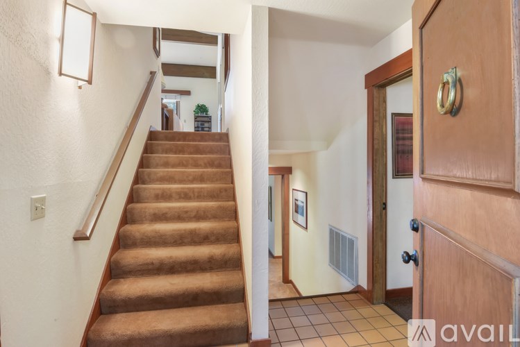 A brown carpeted staircase leads to a second floor.