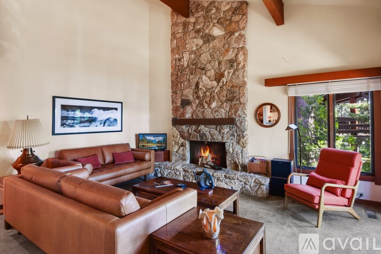 A living room with a stone fireplace and a red chair.