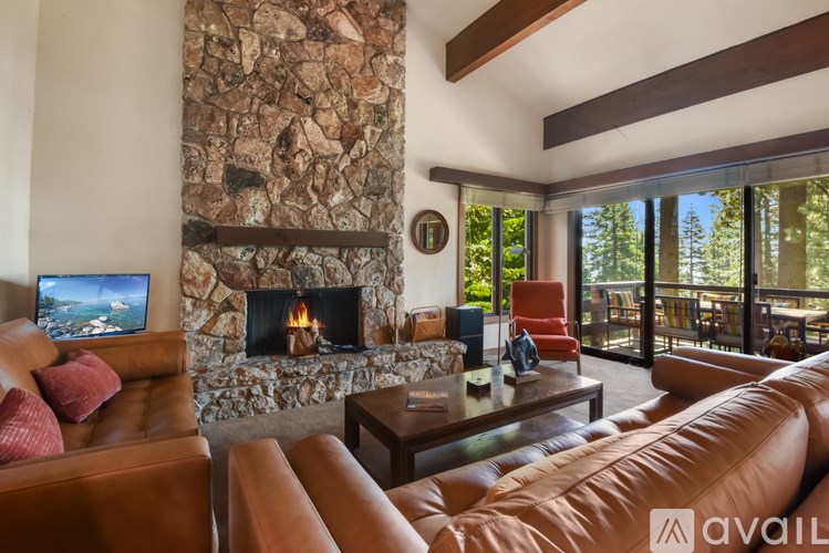 A living room with a stone fireplace and a flat screen TV.