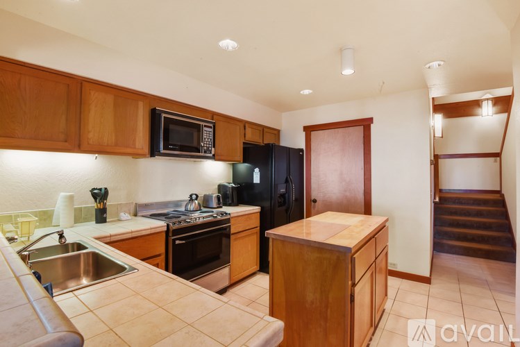 A kitchen with wooden cabinets and a black refrigerator.