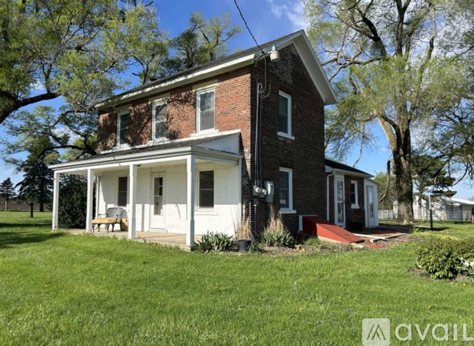 A brick house with a porch and a red front door.