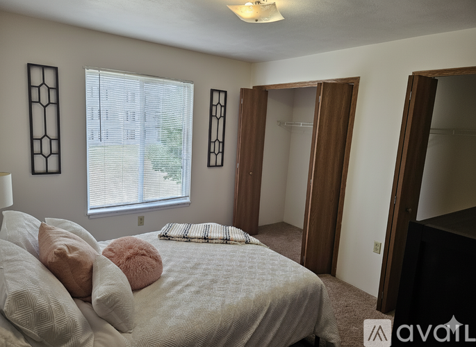 A bedroom with a bed, pillows, and a window.