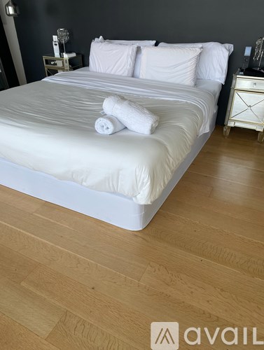 A white bed with a white pillow and towel on top of it.