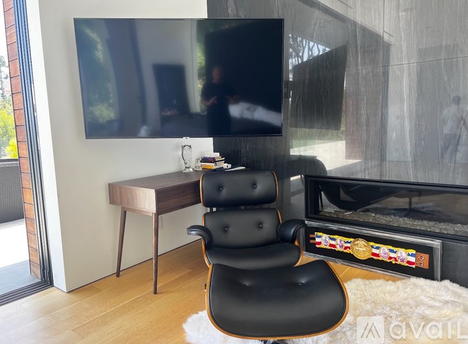 A black leather chair is in front of a fireplace and a television.