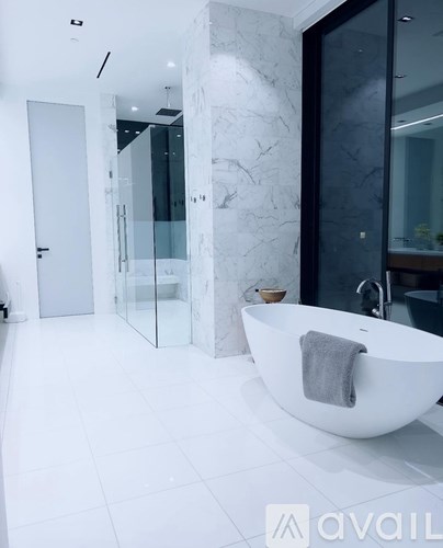 A white bathroom with a marble wall and a white bathtub.