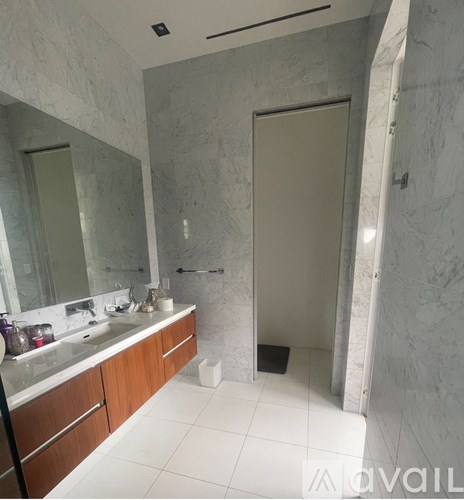 A bathroom with a marble wall and a wooden vanity.
