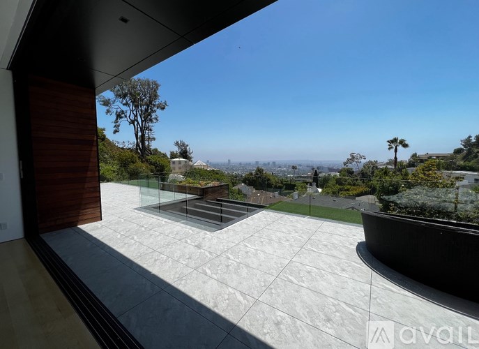 A modern house with a glass balcony overlooking a green landscape.