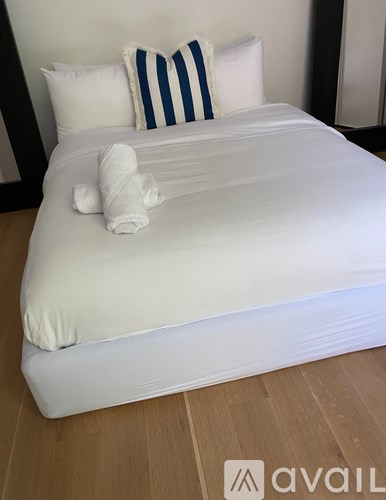 A white bed with a white towel on it.