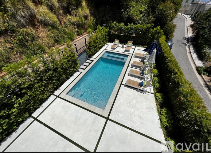 A rectangular pool surrounded by a white tile border and lounge chairs.