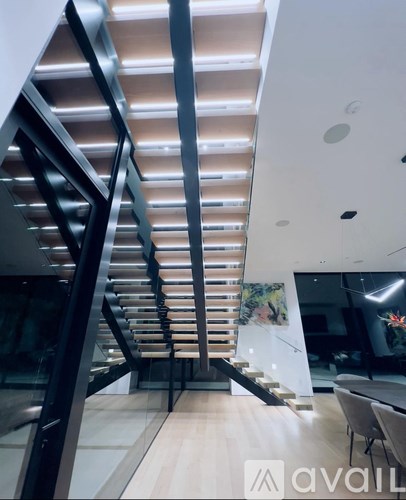 A modern staircase with a metal railing and wooden steps.