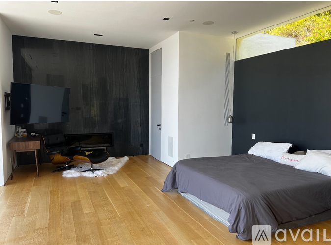 A bedroom with a grey bed and wooden floors.