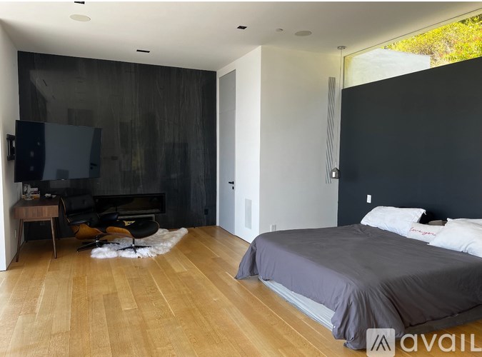 A bedroom with a grey bed and wooden floors.
