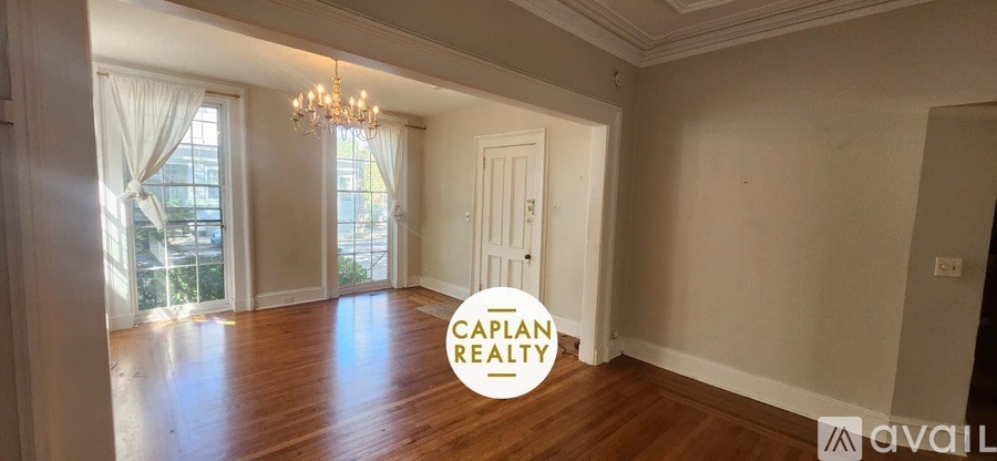A spacious room with wooden floors and a chandelier is available for rent.