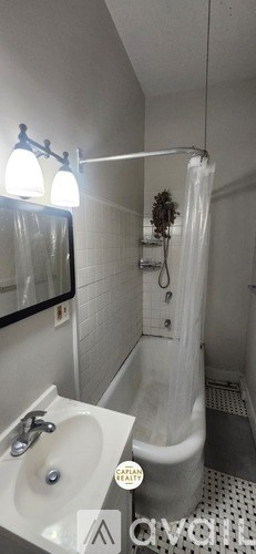 A white bathroom with a sink, mirror, and shower.