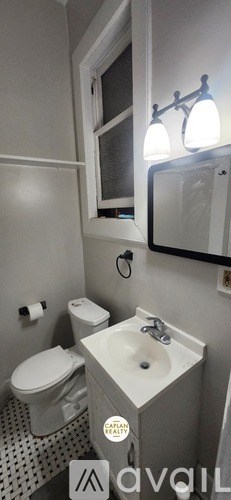 A bathroom with a toilet, sink, and mirror.