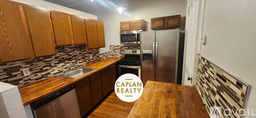 A kitchen with wooden cabinets and a stainless steel refrigerator.