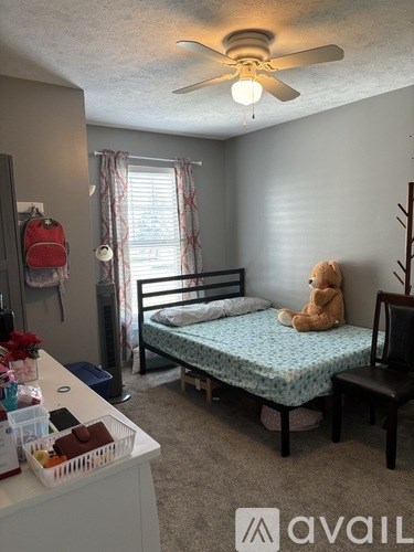 A room with a bed, a chair, and a ceiling fan.