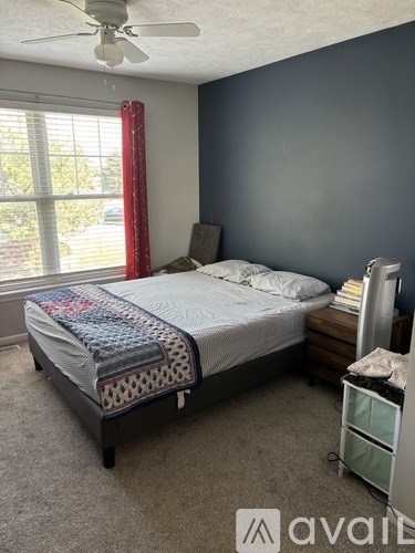 A bedroom with a bed, nightstand, and window.