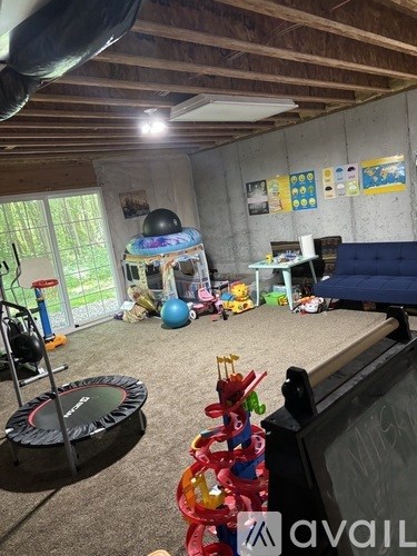 A room with a trampoline, a blue ball, and a black couch.