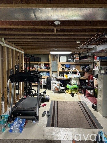 A room with a treadmill, a table, chairs, and a refrigerator.