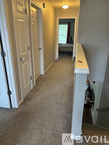 A hallway with a carpeted floor and white walls.