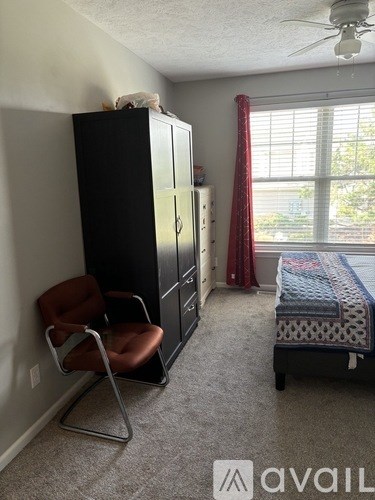 A bedroom with a bed, chair, and cabinet.