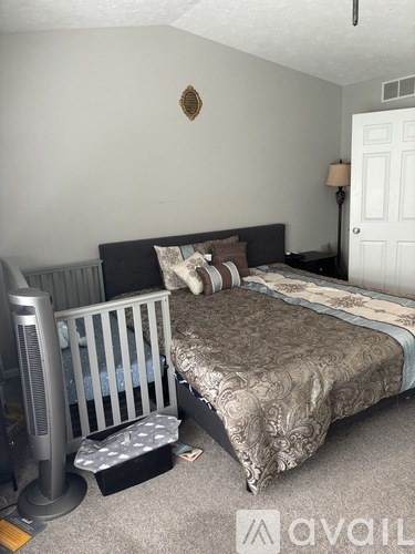 A bedroom with a bed, a television, and a wall-mounted light fixture.
