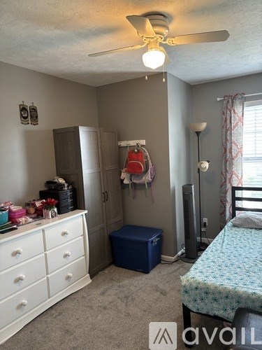 A bedroom with a bed, dresser, and ceiling fan.