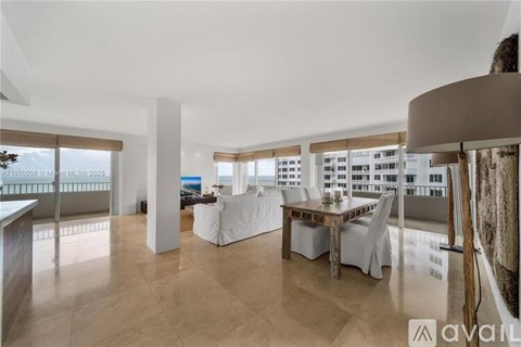 A living room with a dining table and chairs, a couch, and a large window with a view of the city.