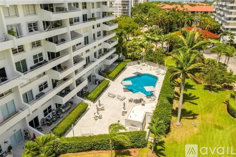 A large white building with a pool in the middle of a grassy area.