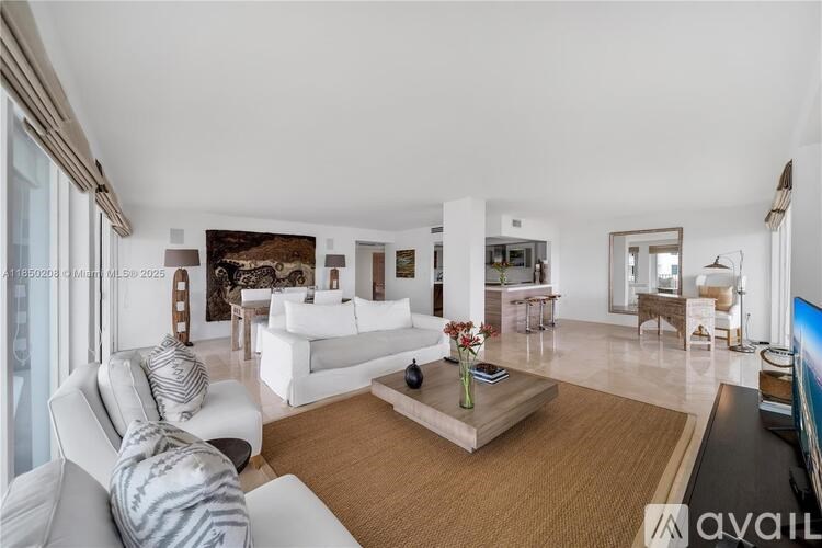 A spacious living room with white furniture and a large window.