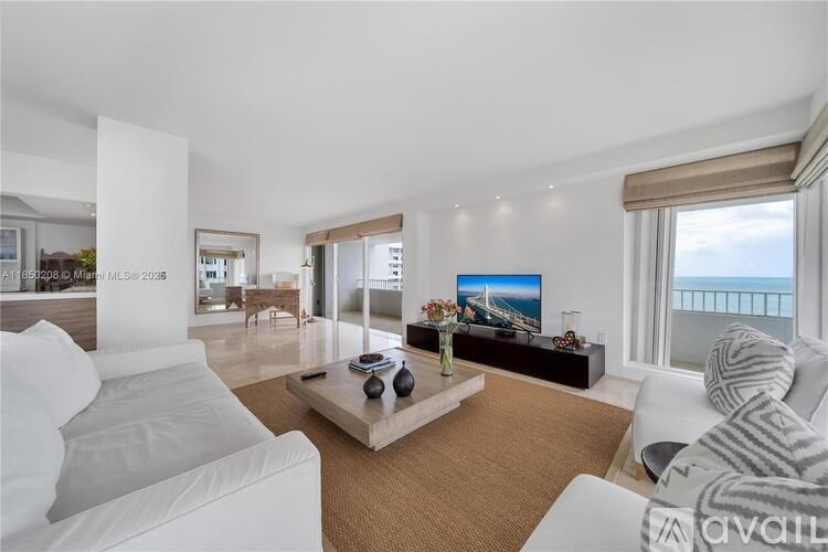 A living room with a large white sofa, a wooden coffee table, and a flat-screen TV mounted on the wall.
