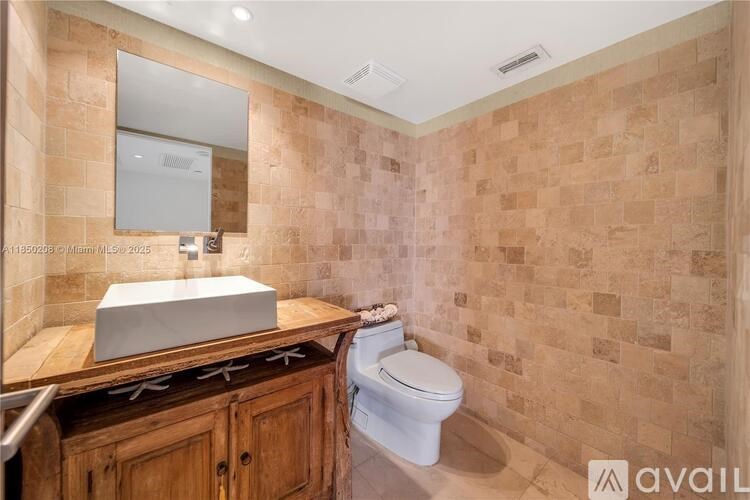 A bathroom with a toilet, sink, and wooden cabinets.
