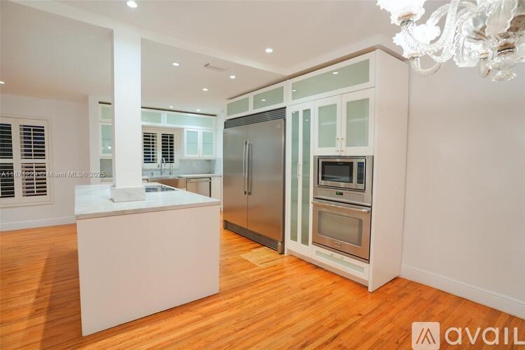 A kitchen with a white island and stainless steel appliances.