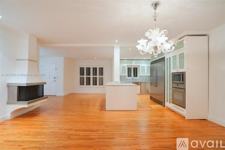 A large, empty room with wooden floors and a chandelier.
