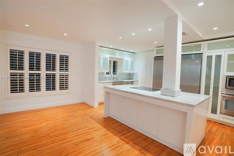 A kitchen with white cabinets and a wooden floor.