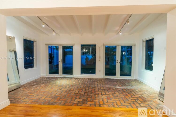 A spacious room with a brick floor and large windows.