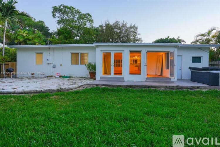 A house with a white exterior and a brown roof is surrounded by green grass.