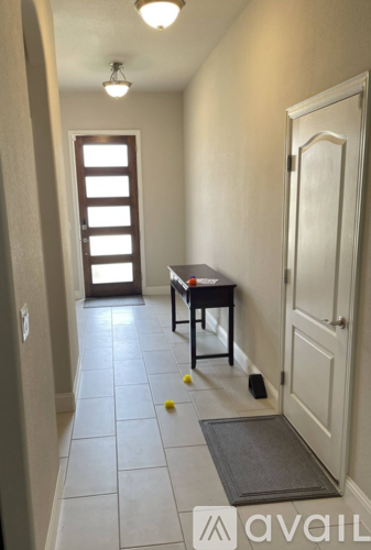 A hallway with a table and chairs and a door.
