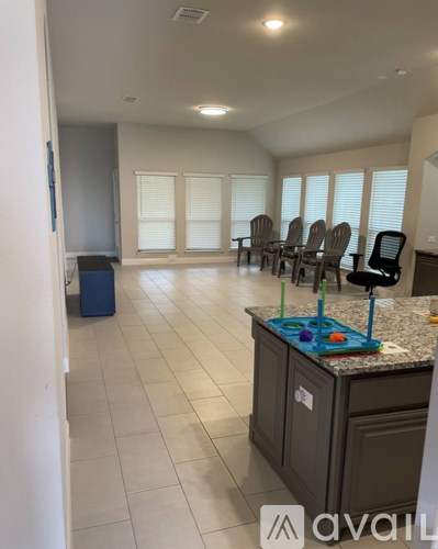 A kitchen with a counter, chairs, and a window.
