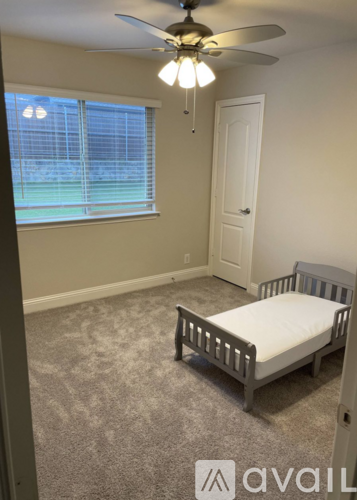 A bedroom with a bed, a ceiling fan, and a window overlooking a fence.