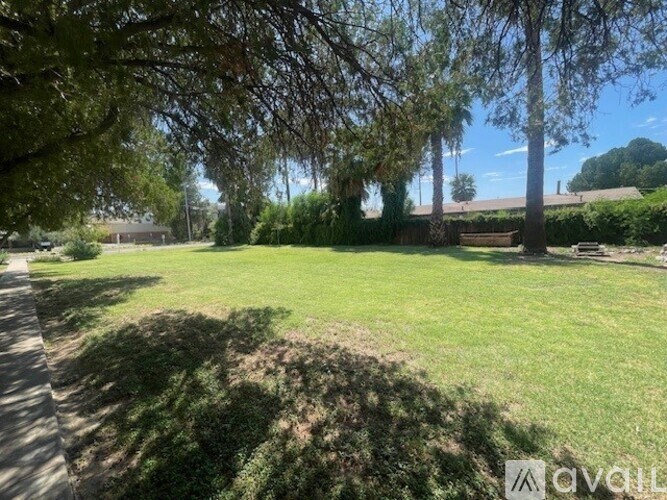 A grassy field with trees and a building in the distance.
