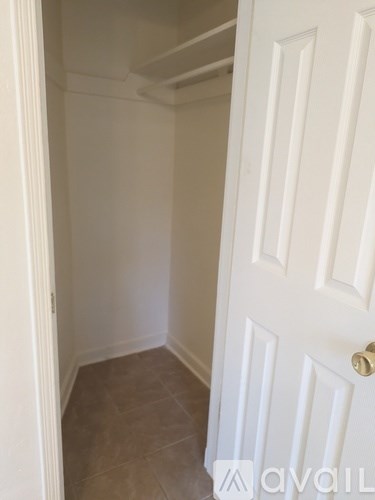 A white door with a gold handle is in a room with tiled flooring.