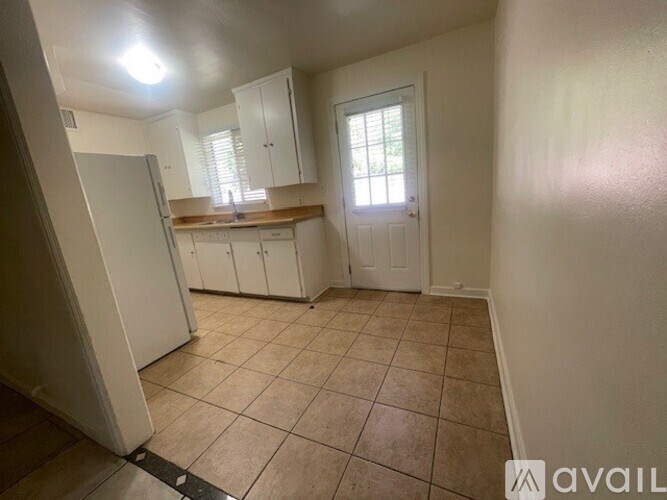 A kitchen with white cabinets and a tiled floor.