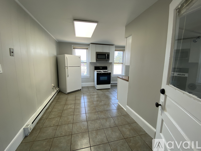 A room with a carpeted floor, two windows, and a door leading to another room.