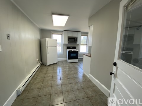 A room with a carpeted floor, two windows, and a door leading to another room.