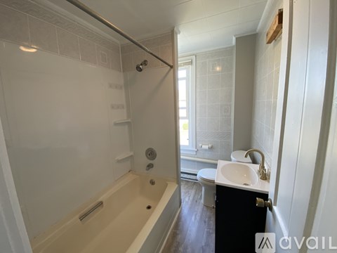A room with a white door and a brown floor with sunlight coming through the window.