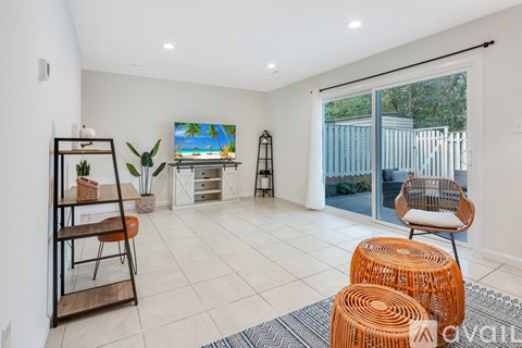 A living room with a white wall and a painting of a beach scene.